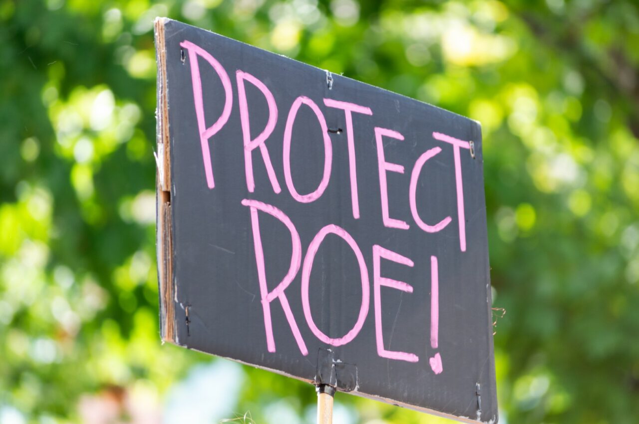 A hand holding a sign supporting protecting Roe v. Wade during a
