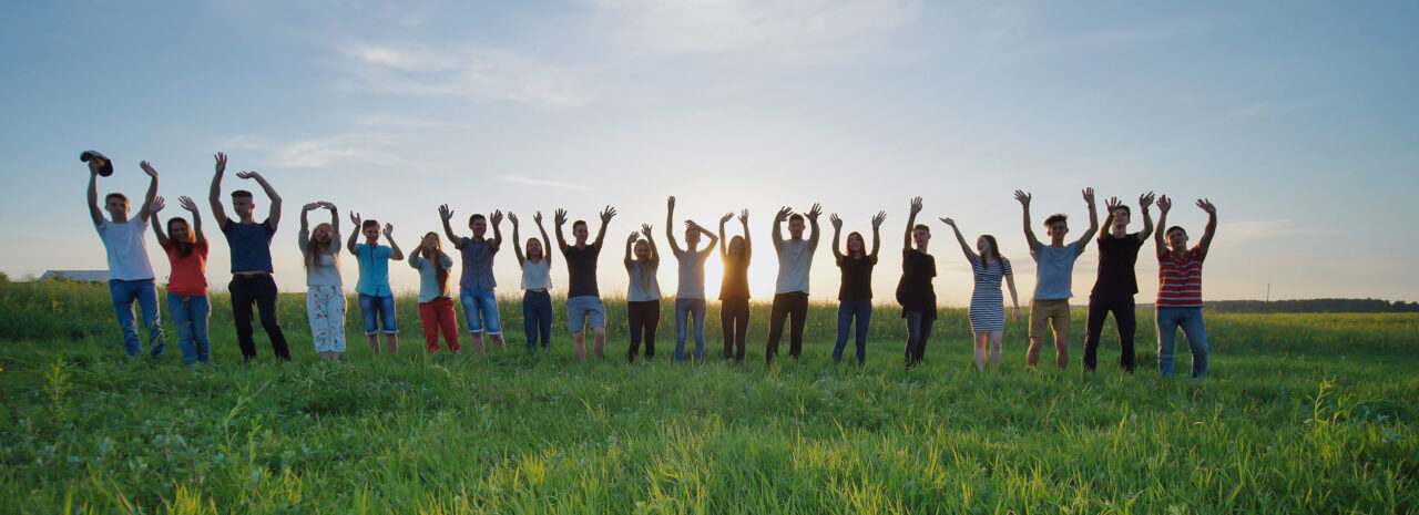 Students say goodbye to the school. Pupils waving their hands against the backdrop of the setting sun.