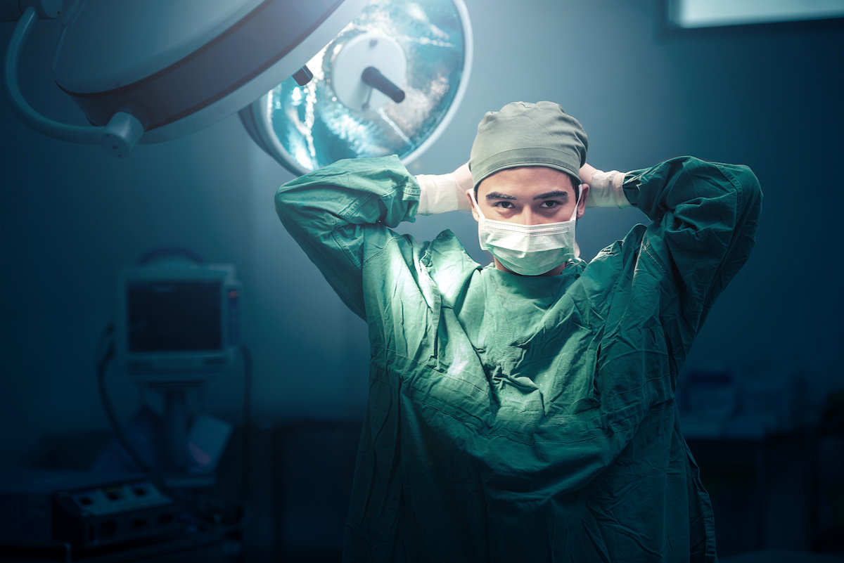 Male surgeon tying mask at operating room