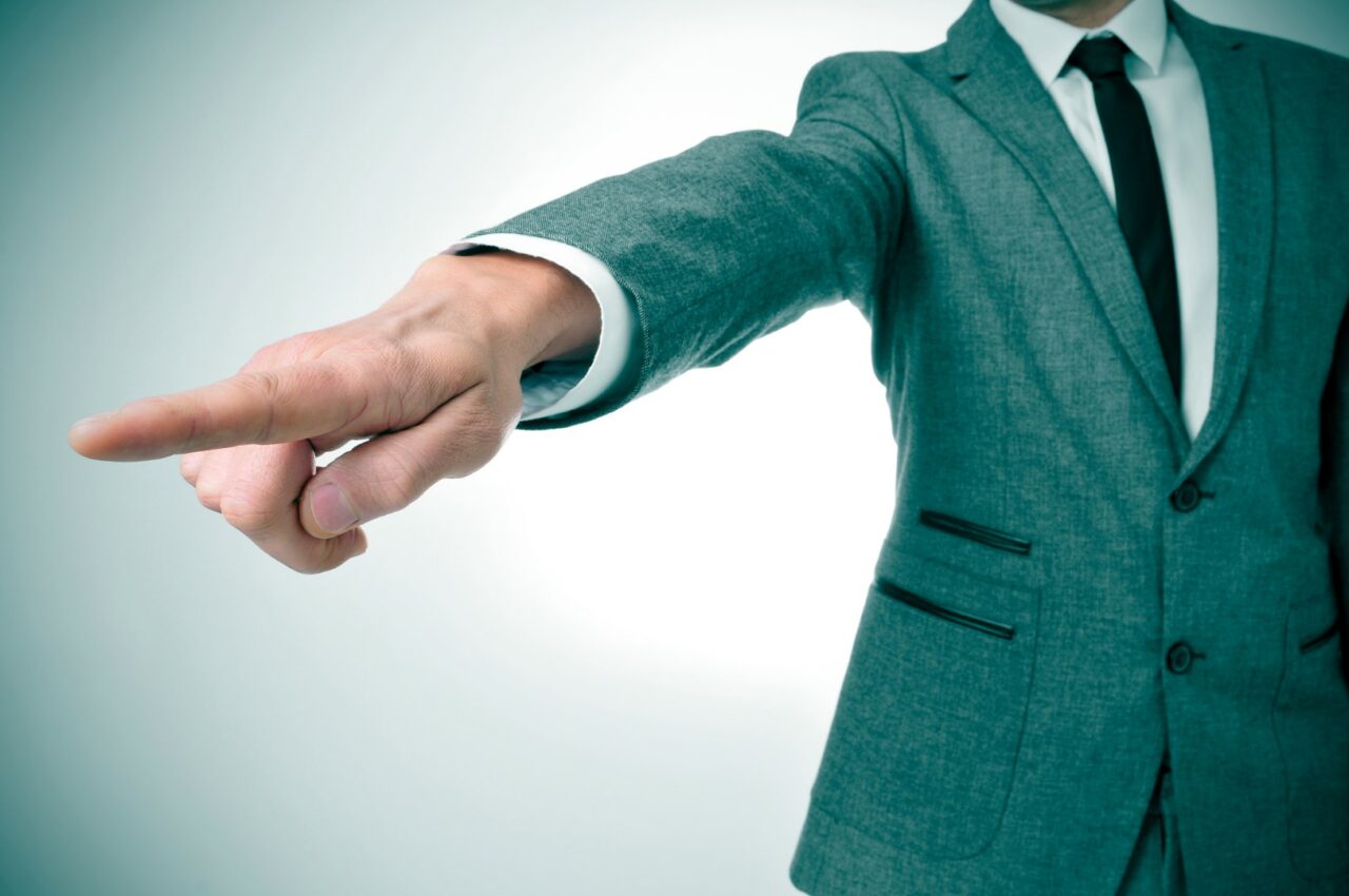 man in suit pointing with the finger the way out