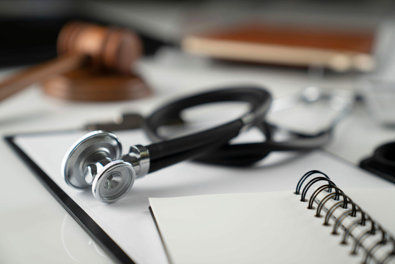 Medical law concept. Gavel, notebook and stethoscope on the whit