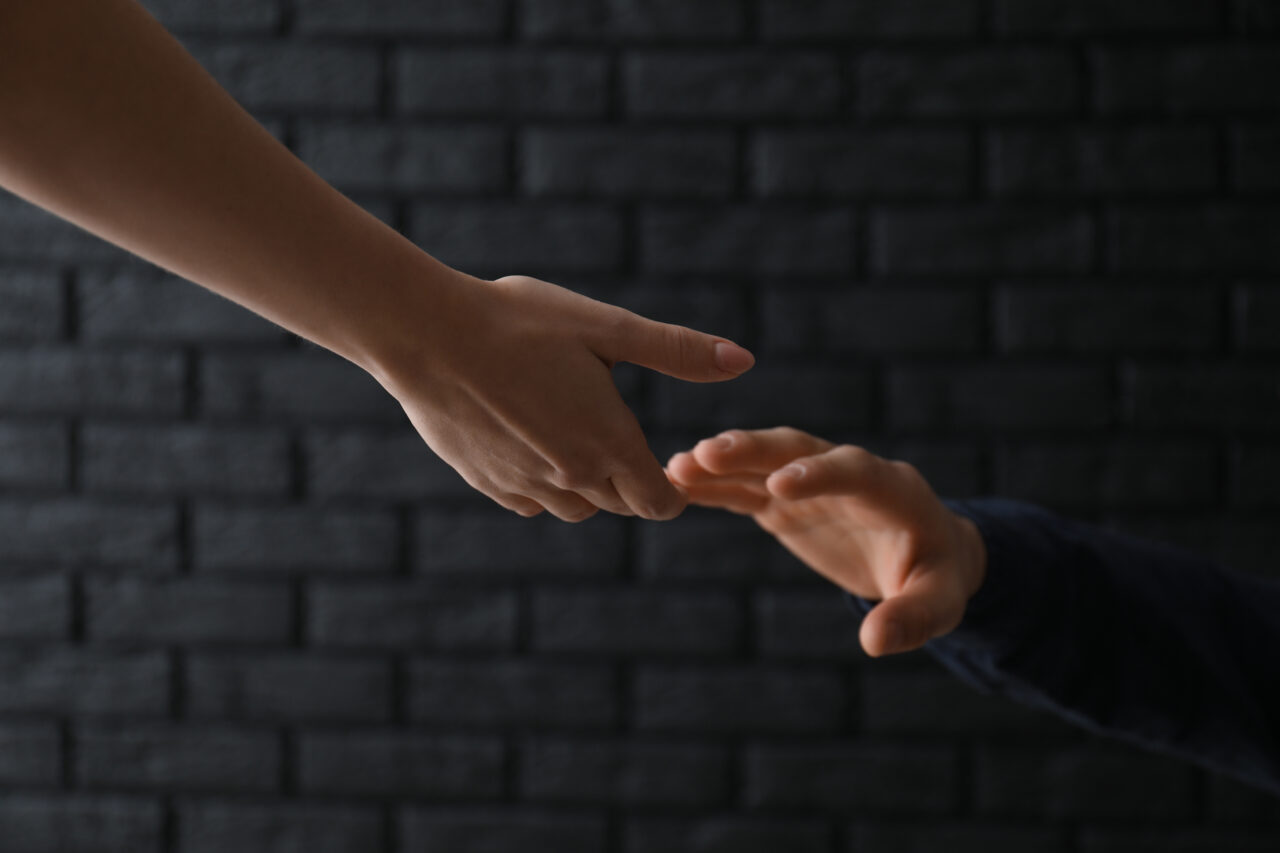 Woman giving hand to depressed man against dark background. Suic