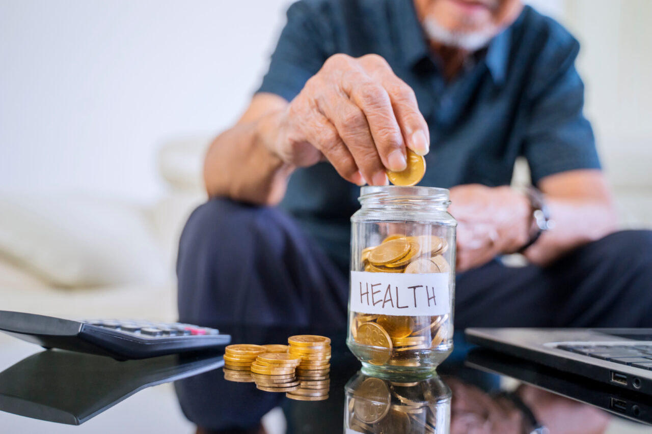 Hand savings coins in a jar with health text