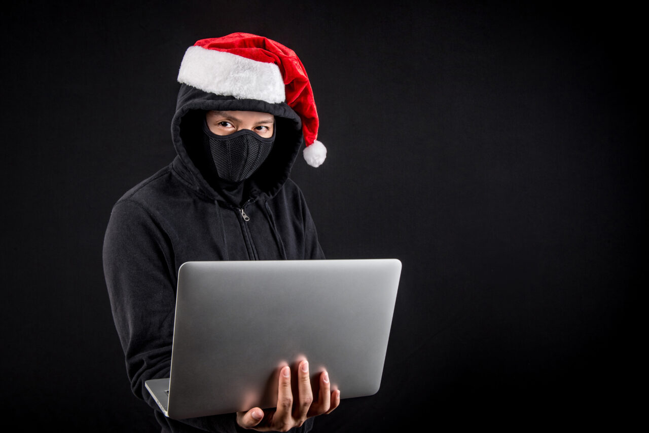 mysterious male santa hacker holding laptop computer