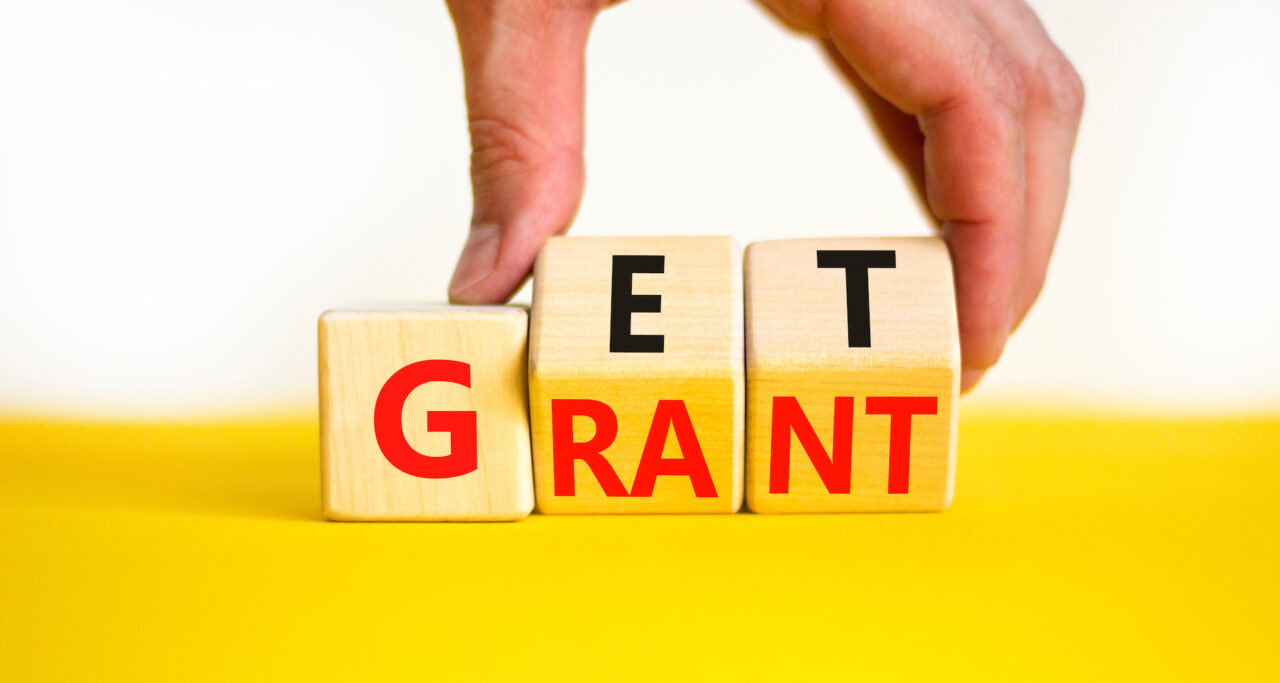 Get grant symbol. Businessman turns wooden cubes with concept words Get grant on a beautiful yellow table white background. Copy space. Business and get grant concept. Grant funding, grant application, grant program