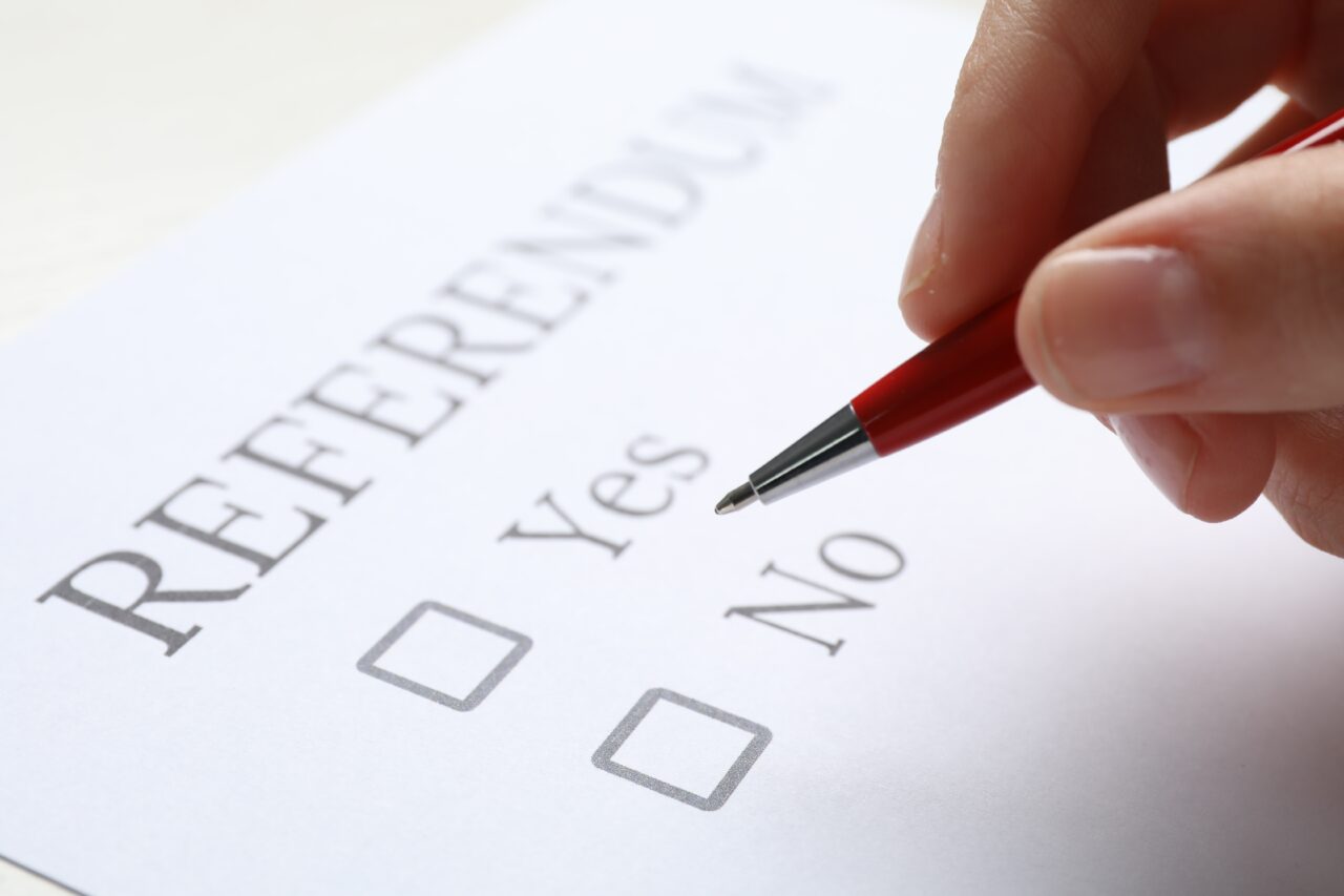 Woman with referendum ballot making decision on white background, closeup