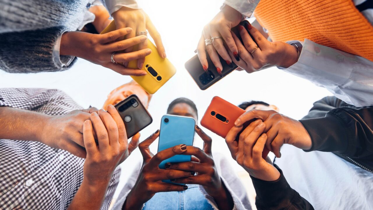 Teens in circle holding smart mobile phones - Multicultural youn