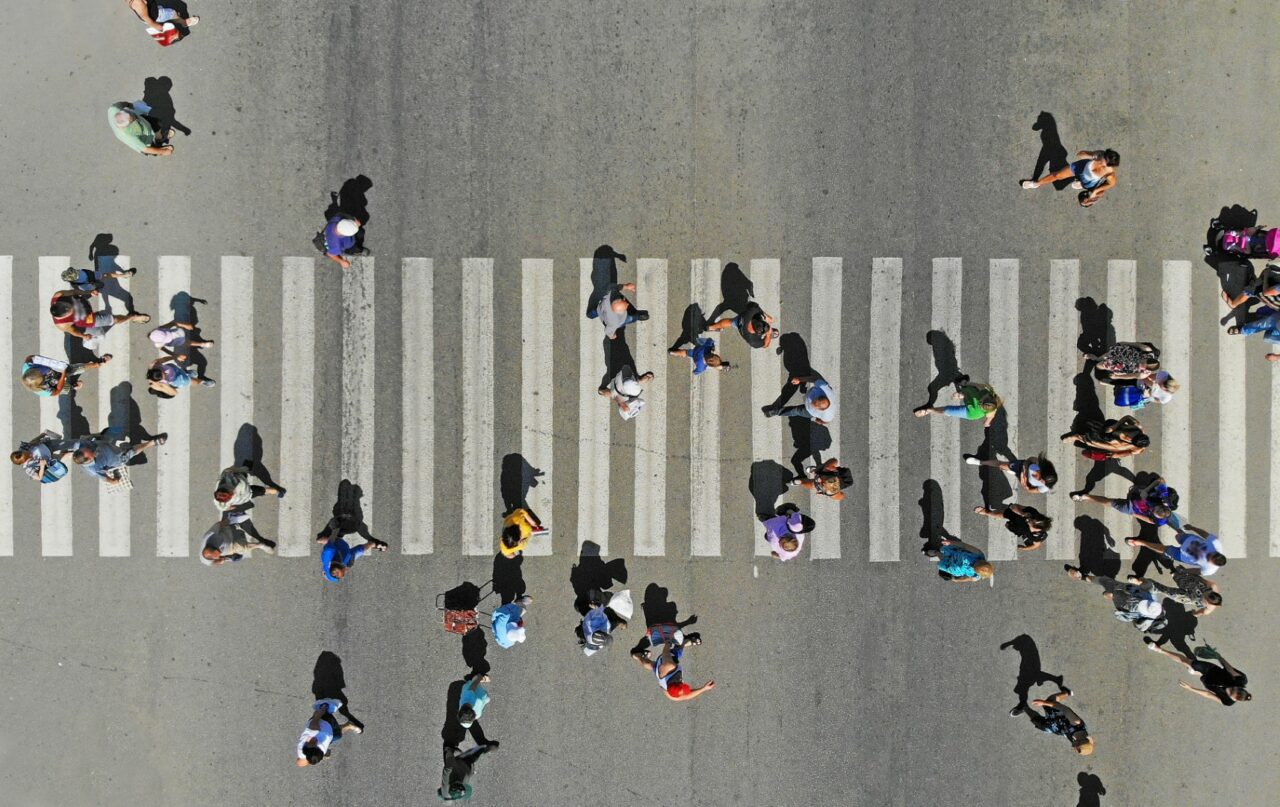 Aerial. People crowd on pedestrian crosswalk. Top view.