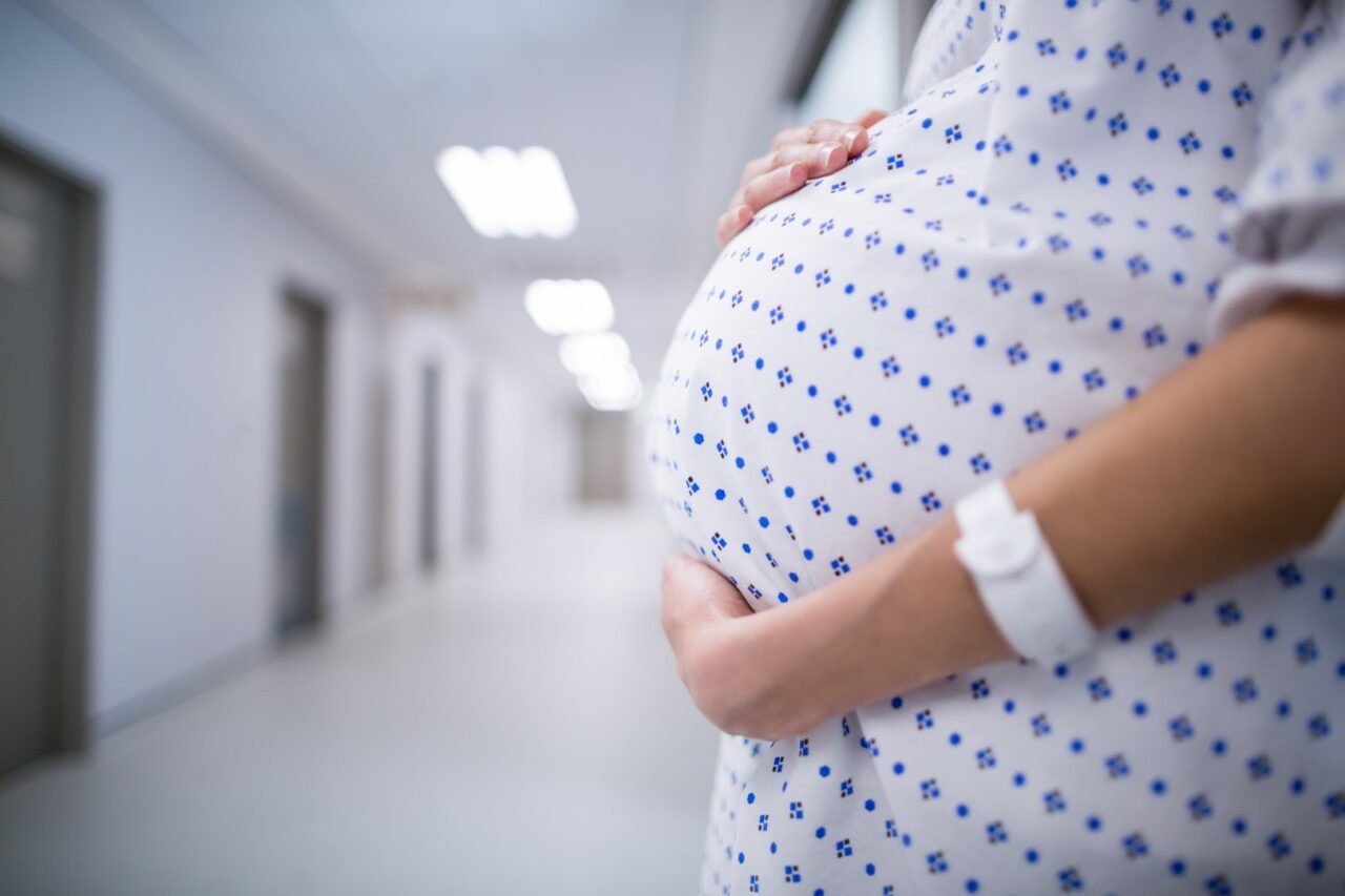 Mid section of pregnant woman standing in corridor