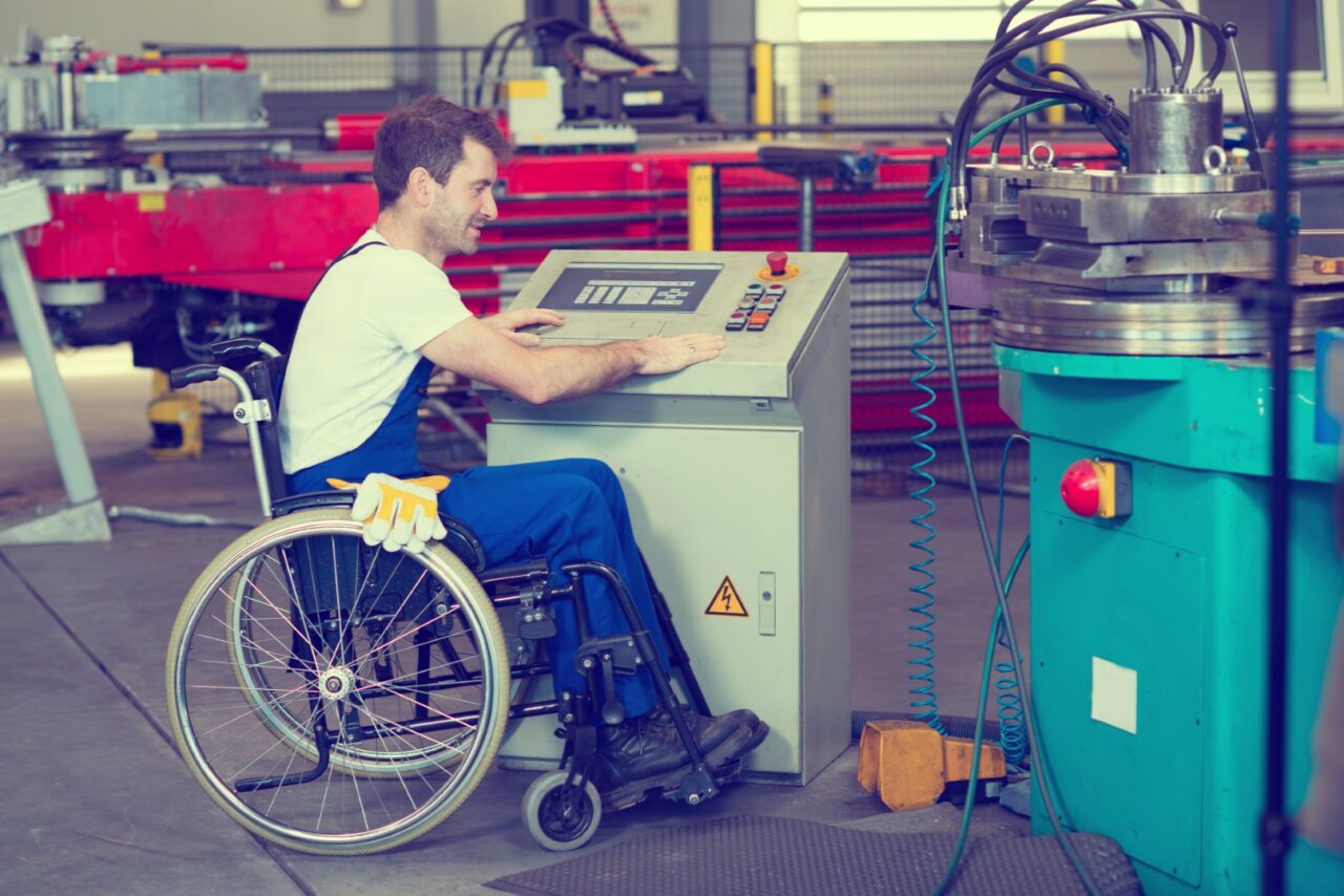 disabled worker in wheelchair in factory on the machine