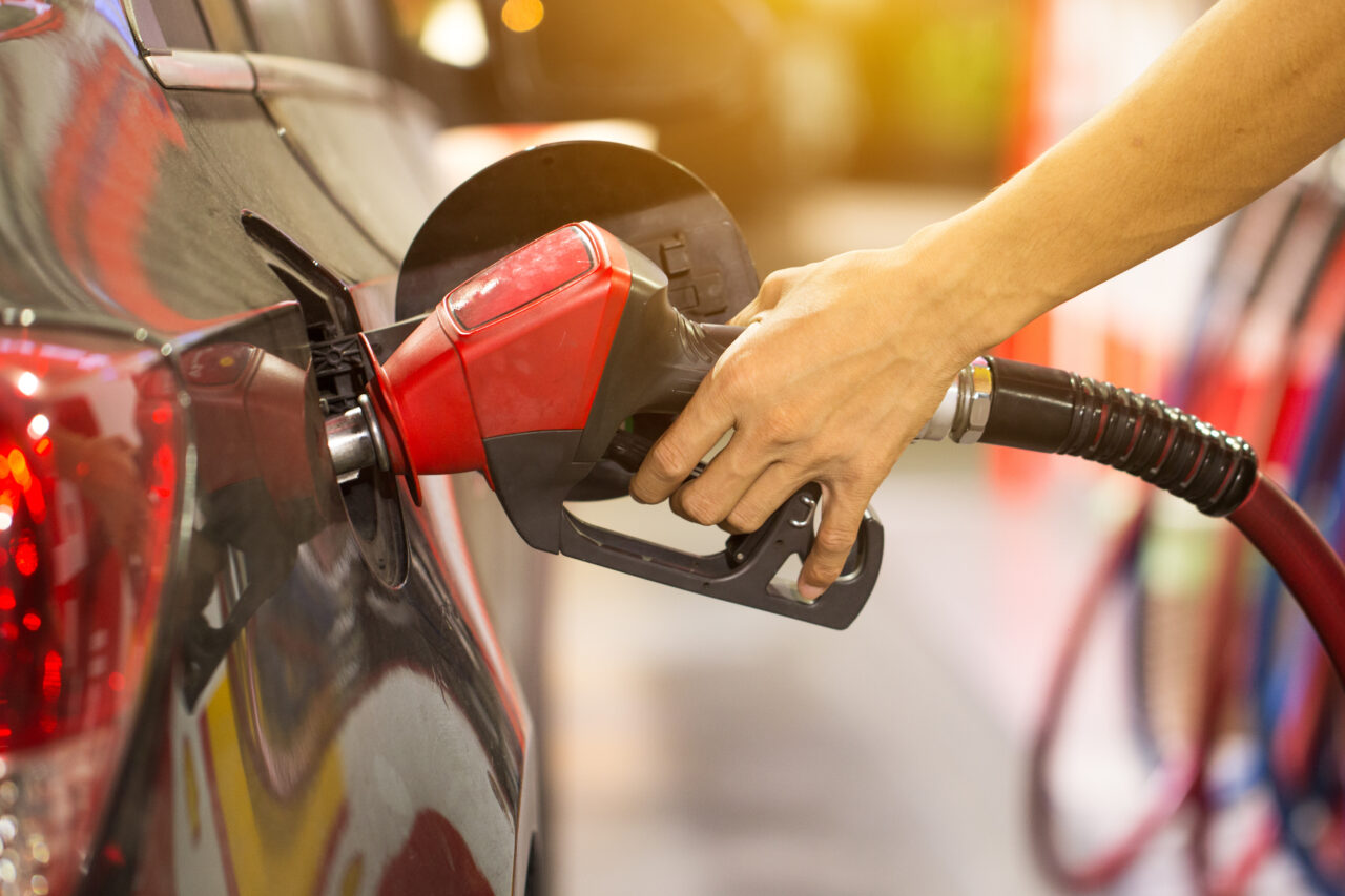 Pumping gas at gas pump. Closeup of man pumping gasoline fuel in