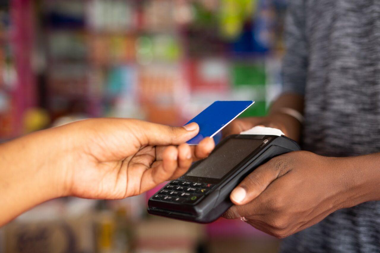 Close up shot of customer paying money by tapping credit card to swiping machine at grocery shop - concept of digital payment, contact less transaction, and safety