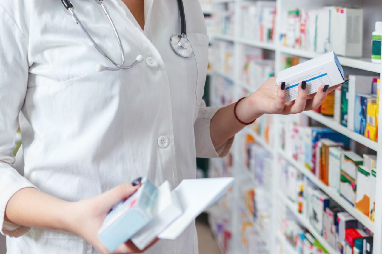 Woman pharmacist holding prescription checking medicine in pharm