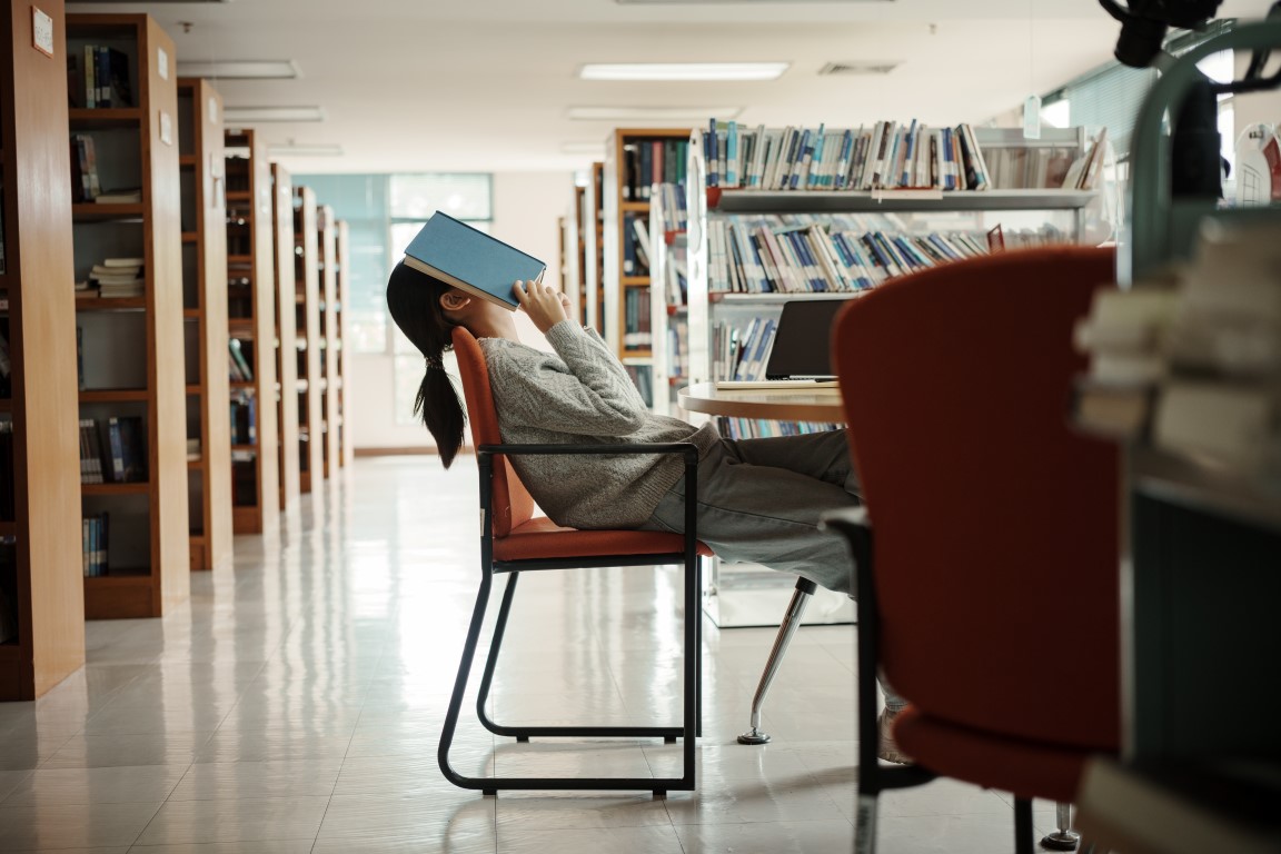 Asian student woman read books in library at university. Young girl stress tired have problem while study hard. Sadness concept