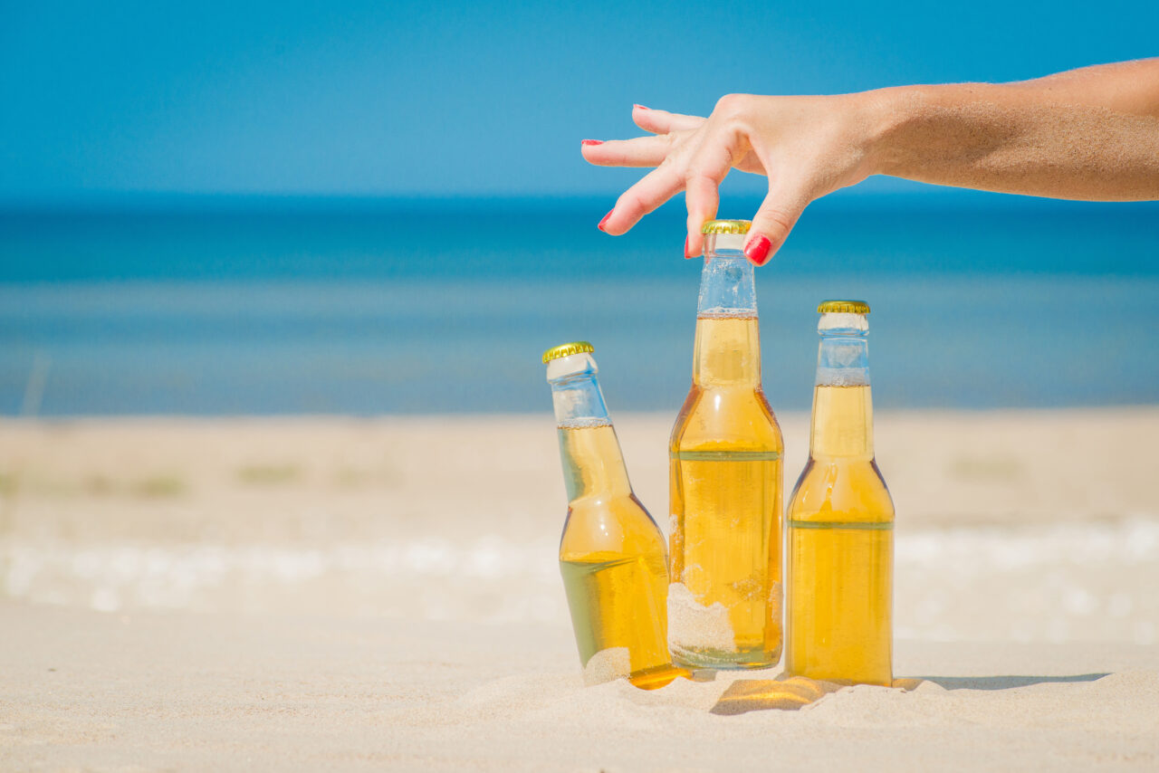 Ice cold beer bottles in the sand under the sun