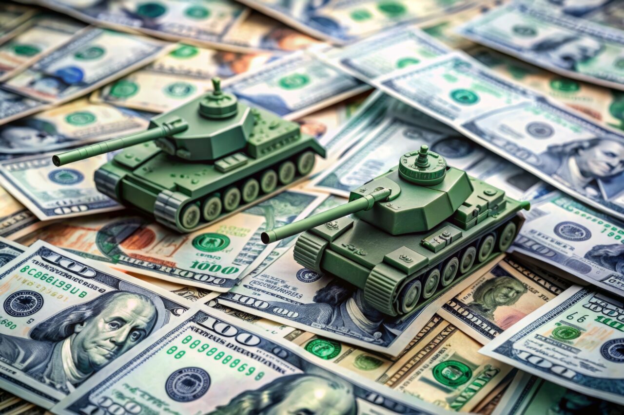 Tanks are placed on top of dollar bills. A metaphor for currency warfare, financial crises, trade wars, tariff penalties, international competition, war costs, and military spending.