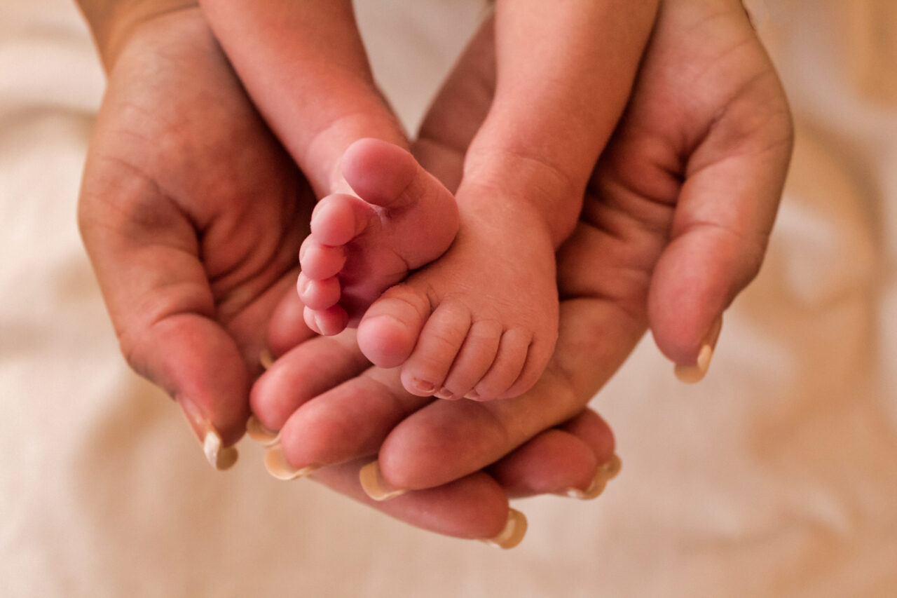 Feet of newborn baby in the hands of the mother.