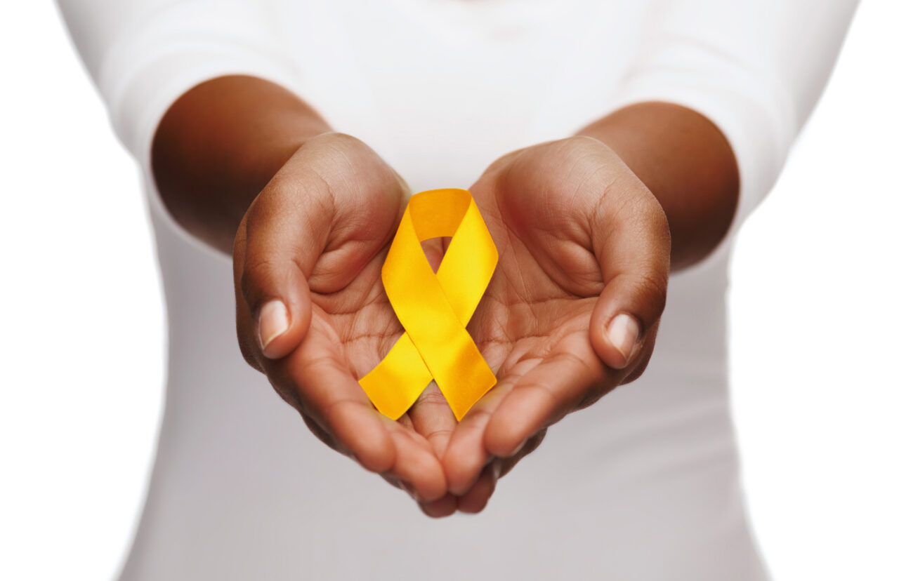 hands holding yellow gold cancer awareness ribbon