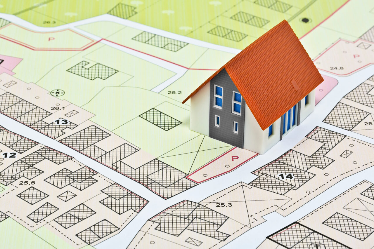 New home and free vacant land for building activity - Construction industry concept with a residential building, imaginary cadastral map, General Urban Planning and zoning regulations