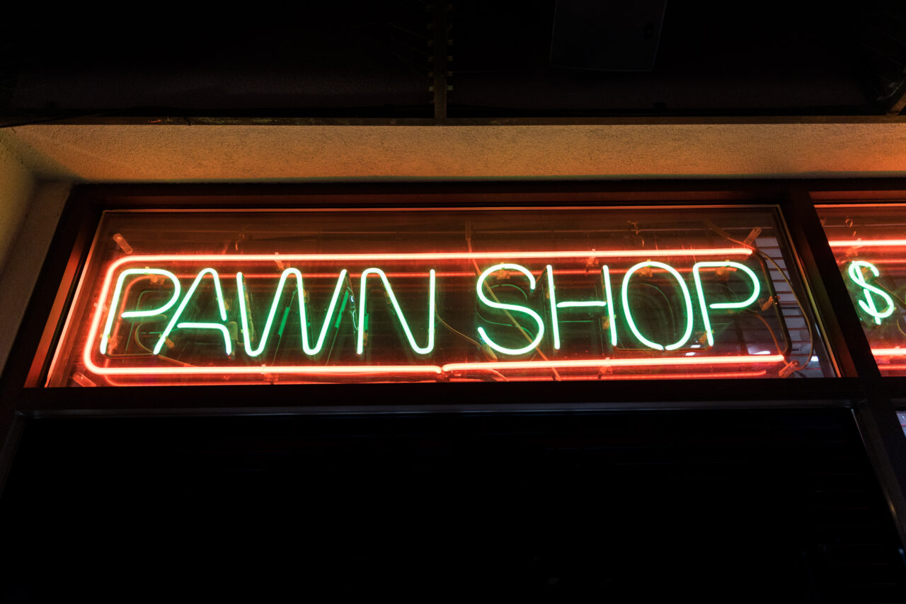 Pawn shop sign glowing from a dark window