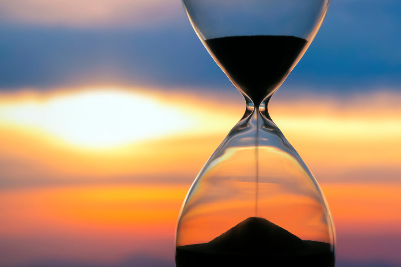 Hourglass on the background of a sunset. The value of time in li