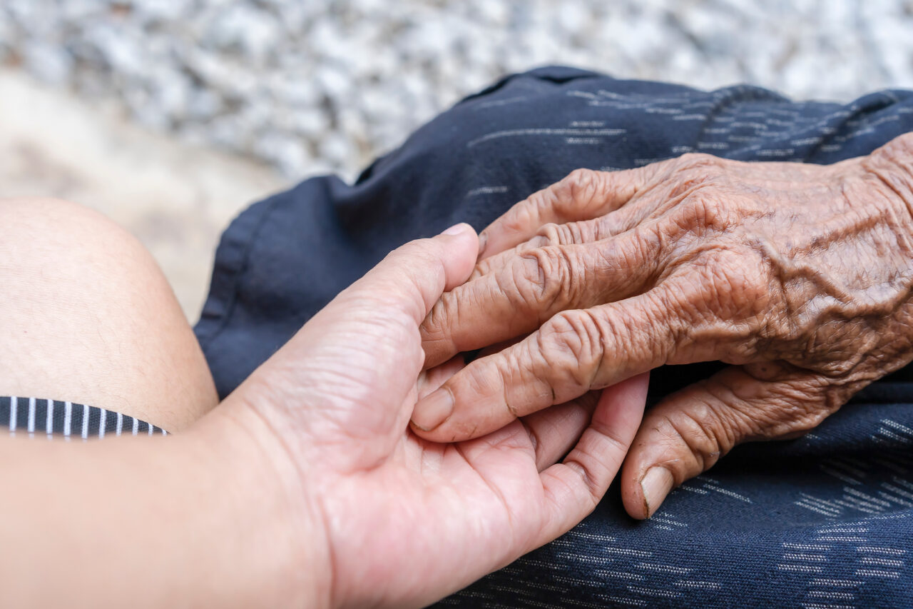 Close-up of old and young holding hands. Middle-aged mommy's wrinkled hands holding young daughters, a millennial woman supporting mature mum, showing care, and love. Support for the elderly concept.