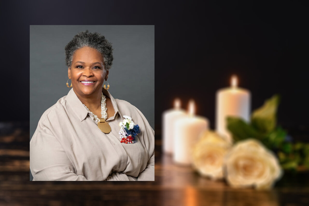 Burning candles and flowers on table against black background