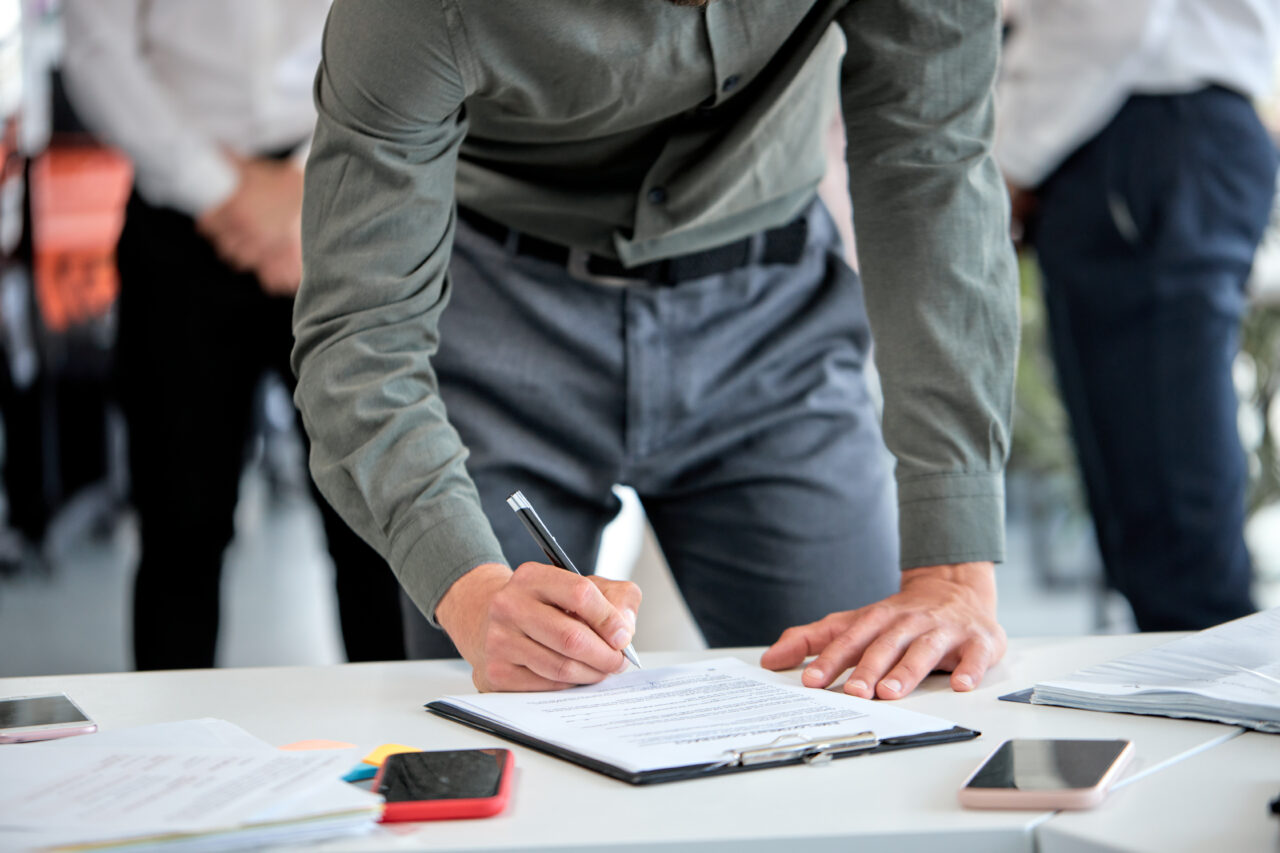 Cropped business man signing financial contract, put write signature on document