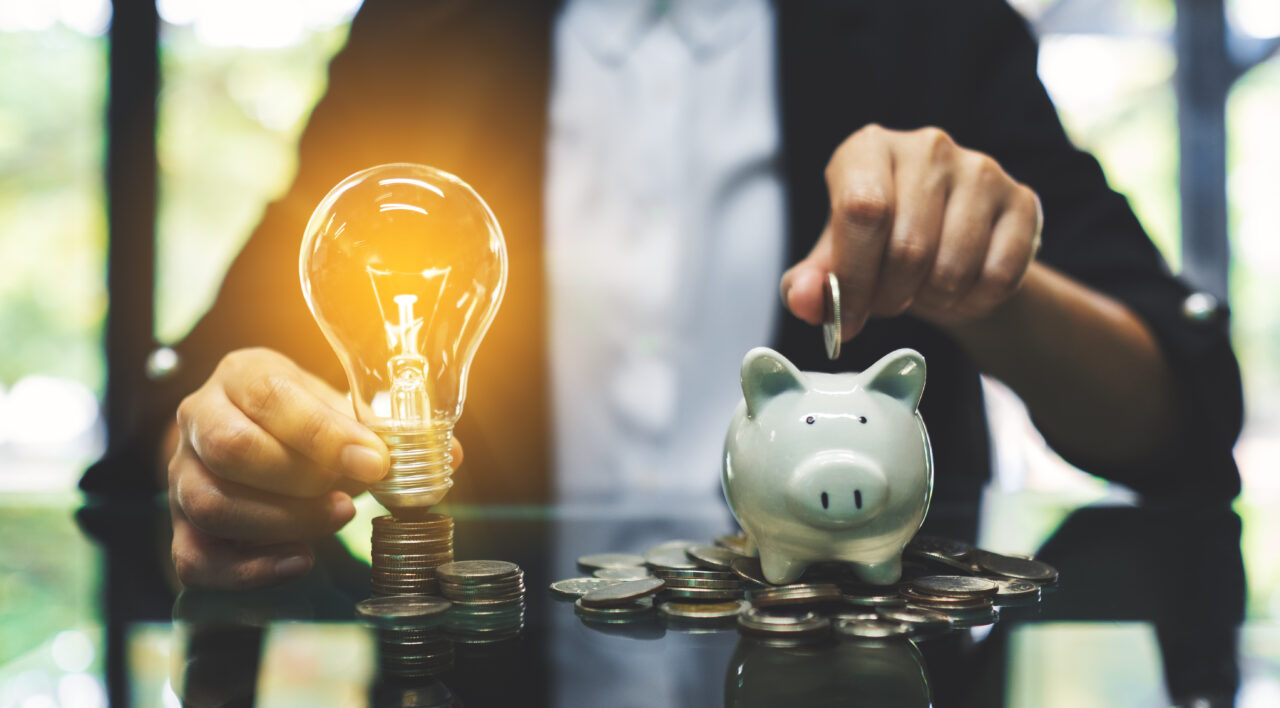 A businesswoman putting coin into piggy bank and a light bulb ov